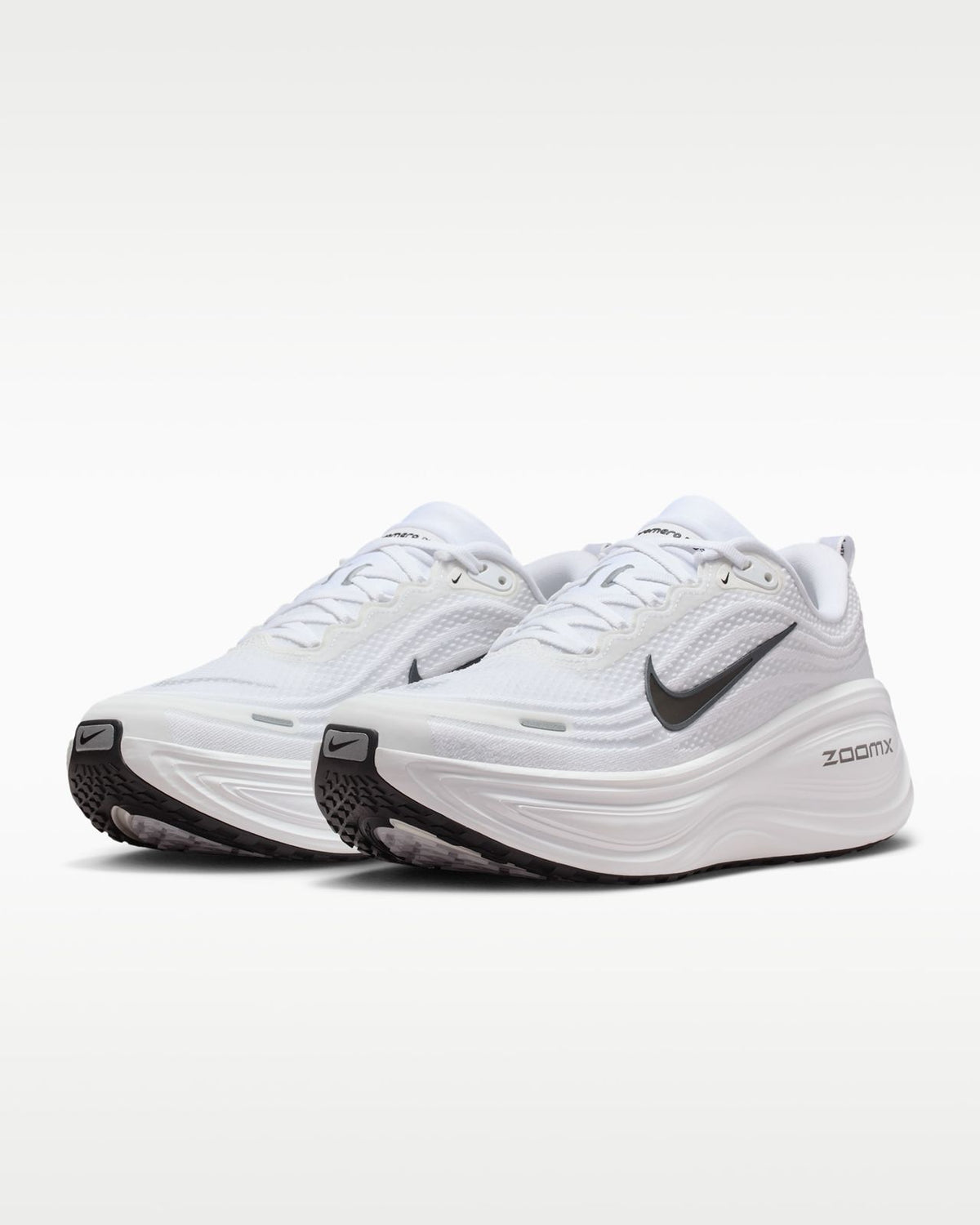 Nike Vomero Plus white running shoes with Nike branding, featuring a sleek white design and cushioned soles for comfort.