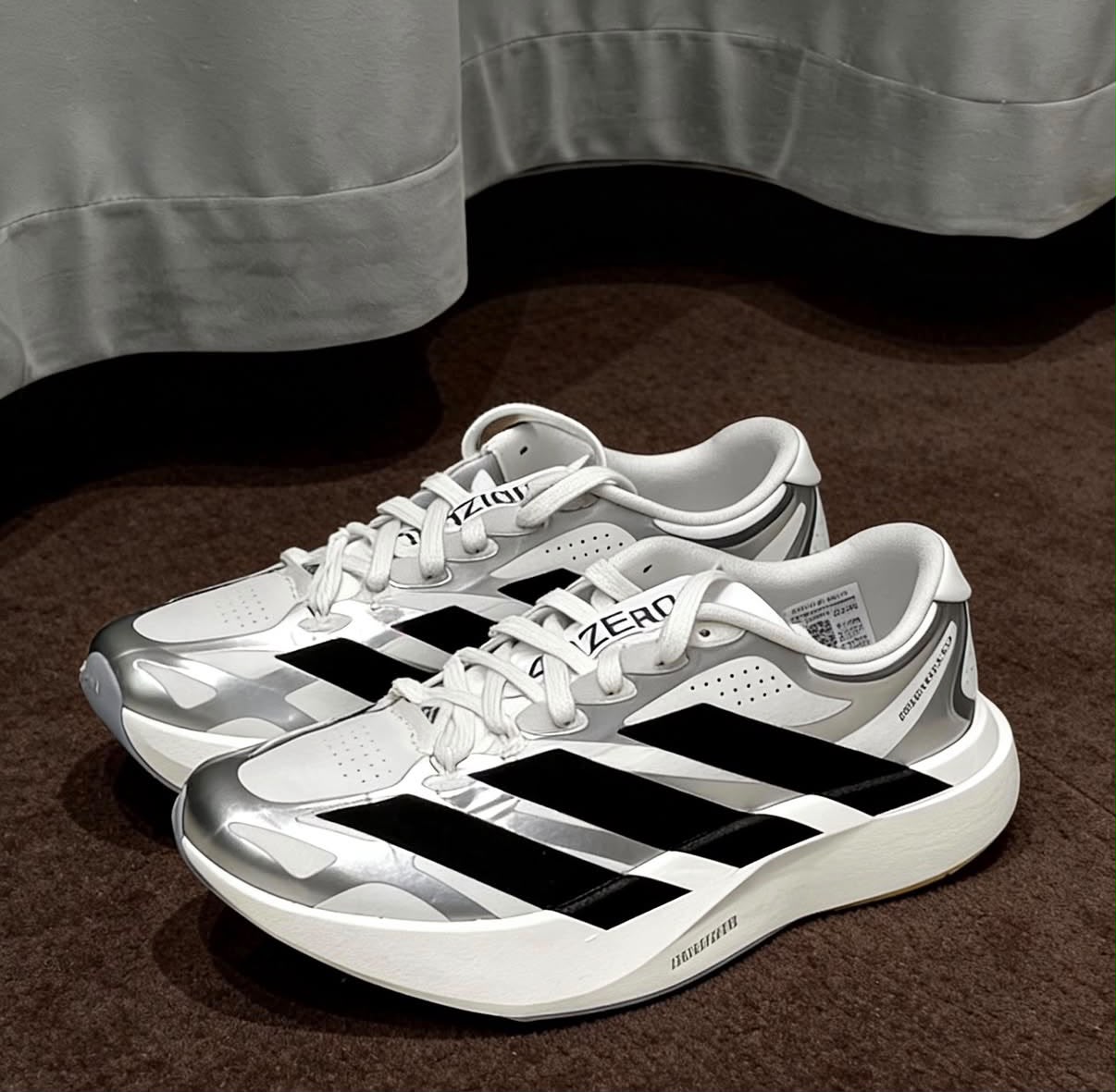 White, black, and silver adidas Adizero EVO SL EXO running shoes with sleek design and breathable mesh uppers.